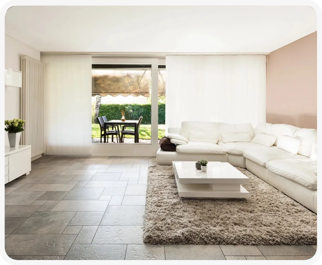 A living room with white furniture and a large rug.